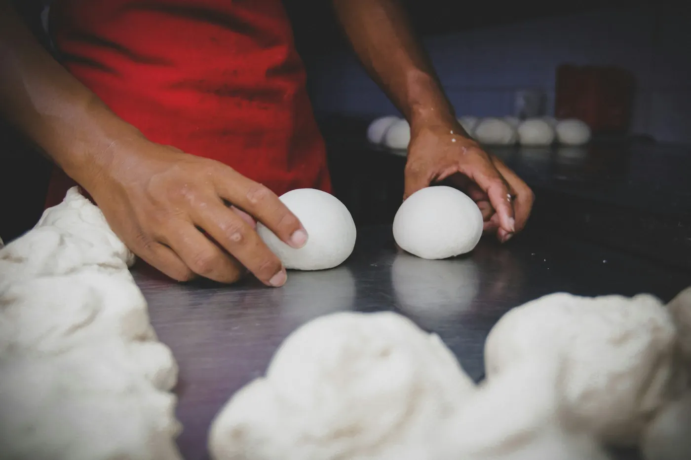 Hands rolling masa dough into balls on a work surface
