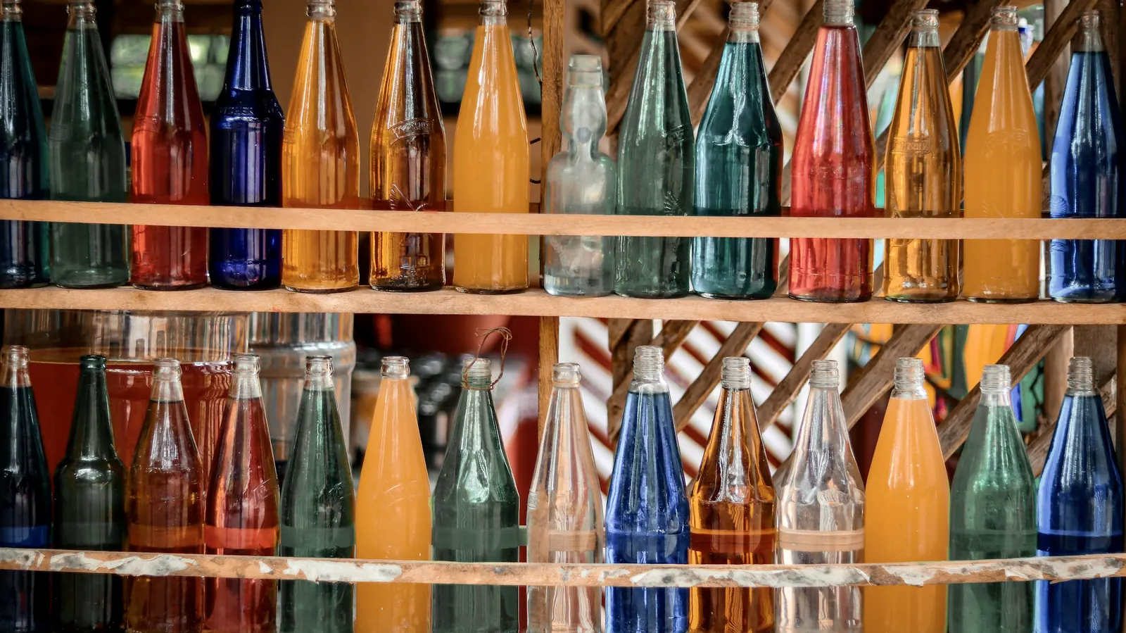 Shelves lined with glass bottles of brightly colored fruit sodas