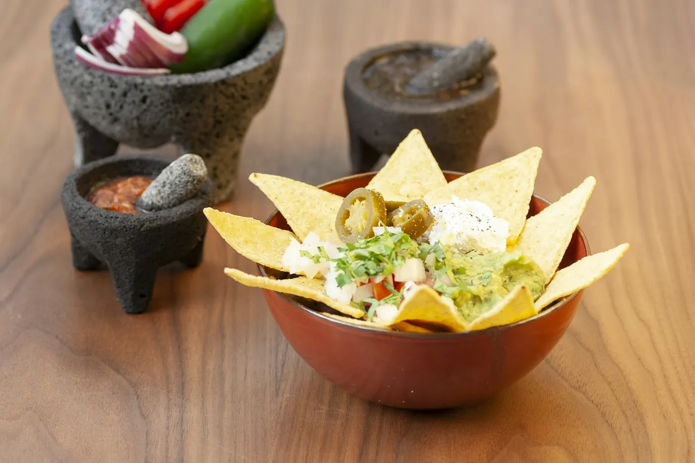 Salsas served in small stone molcajetes beside a bowl of tortilla chips