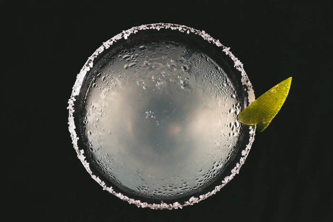 An overhead view of a salt-rimmed glass with a lime wedge
