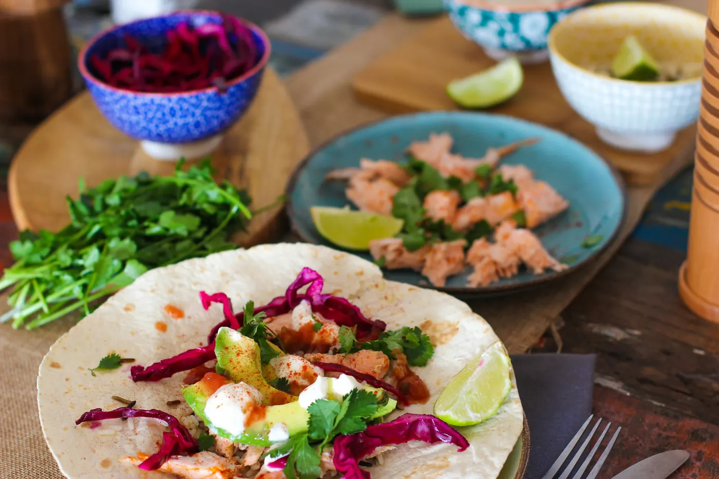 Seafood tacos and small bowls of garnish spread across a table