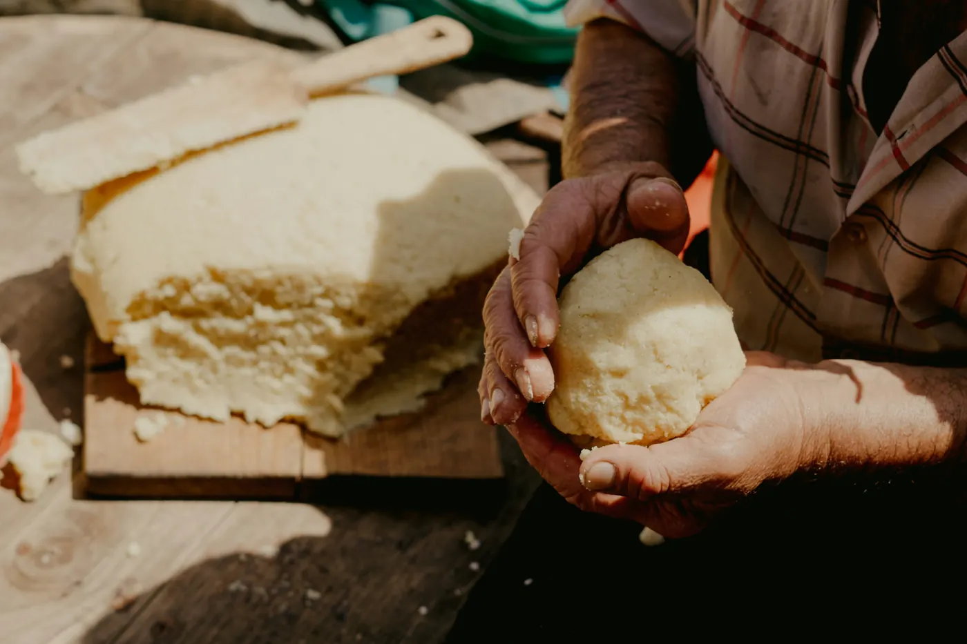 Hands shaping masa dough beside a block of fresh masa