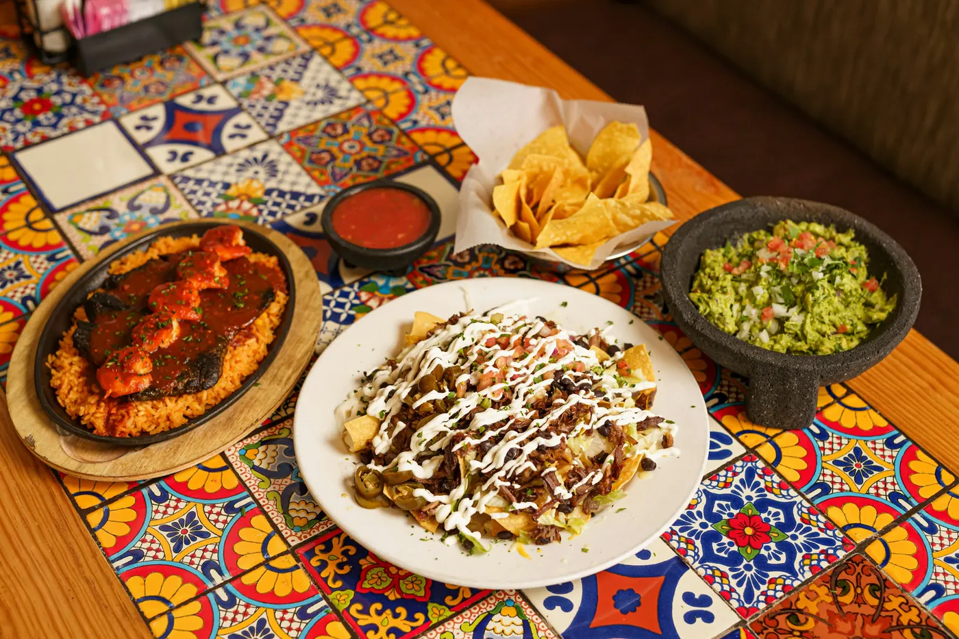 Shared plates of Mexican food and guacamole on a brightly tiled table