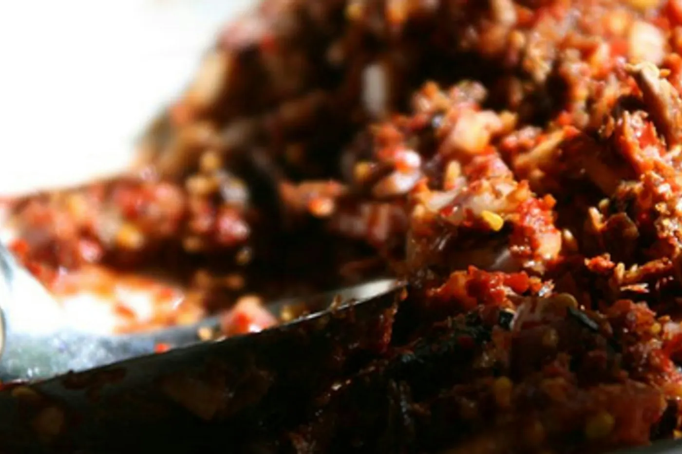 Shredded cooked meat coated in a deep red-orange sauce