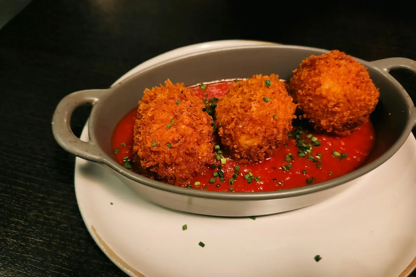 Round shrimp cakes sitting in a pool of red chile sauce