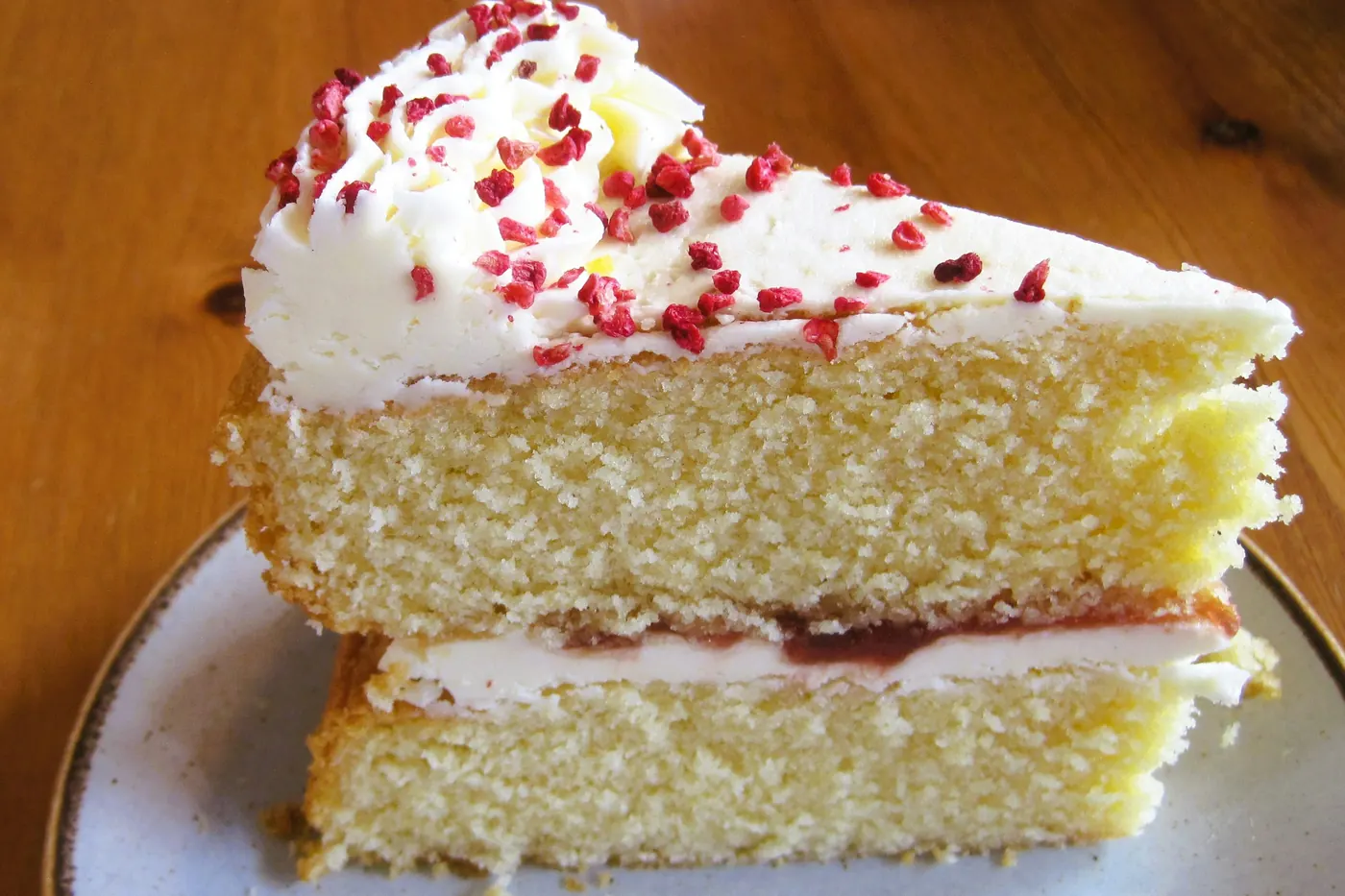 A tall slice of milk-soaked sponge cake with whipped cream on a plate