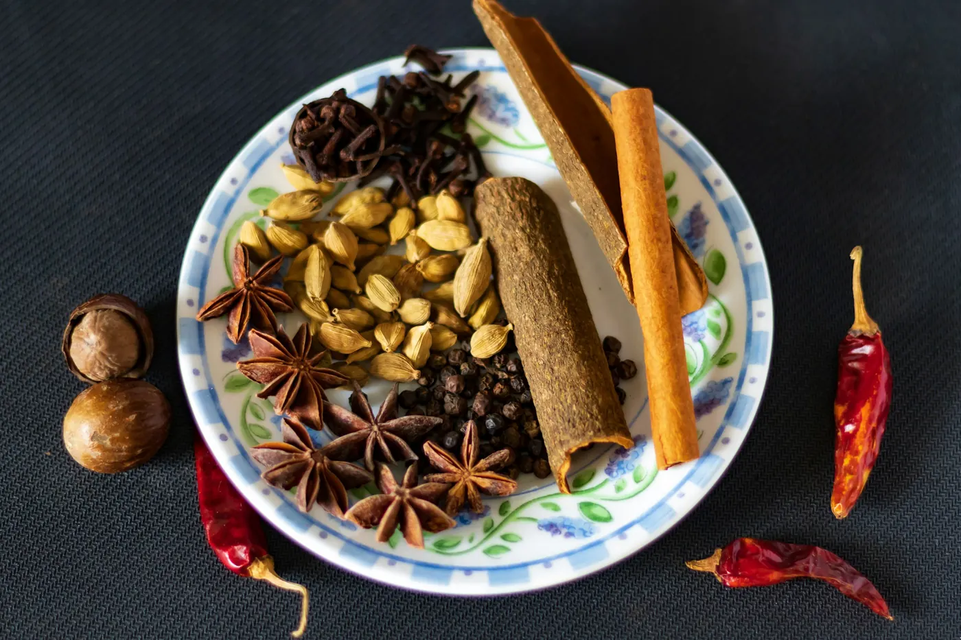 Star anise, cinnamon sticks, nuts and dried chiles arranged on a plate