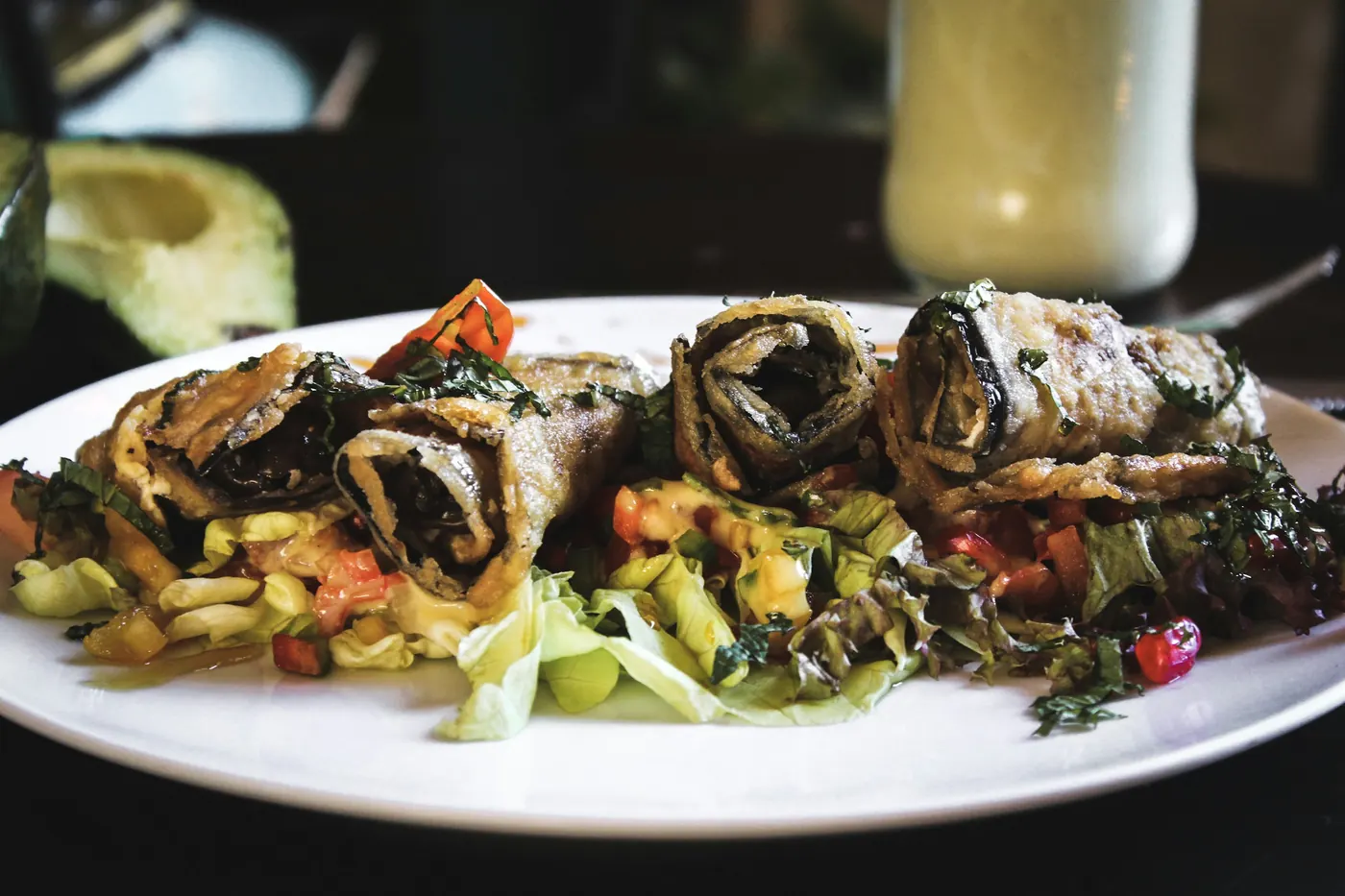 Rolled enchiladas filled with spinach and mushroom on a white plate