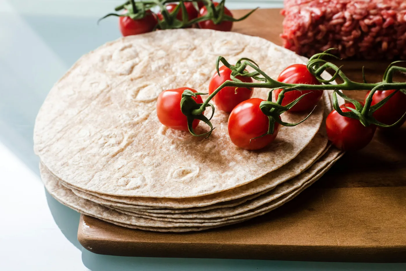 A stack of large flour tortillas on a wooden board