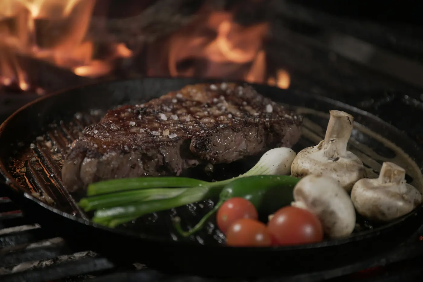 A steak in a cast iron skillet with mushrooms, tomatoes and peppers