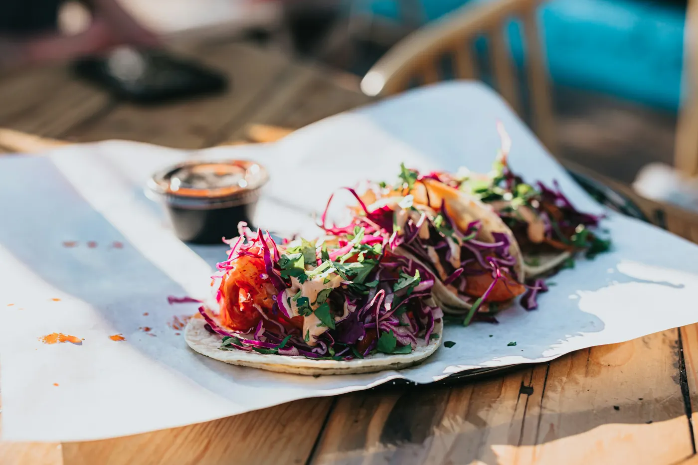 Tacos topped with shredded cabbage and pickled onion on paper