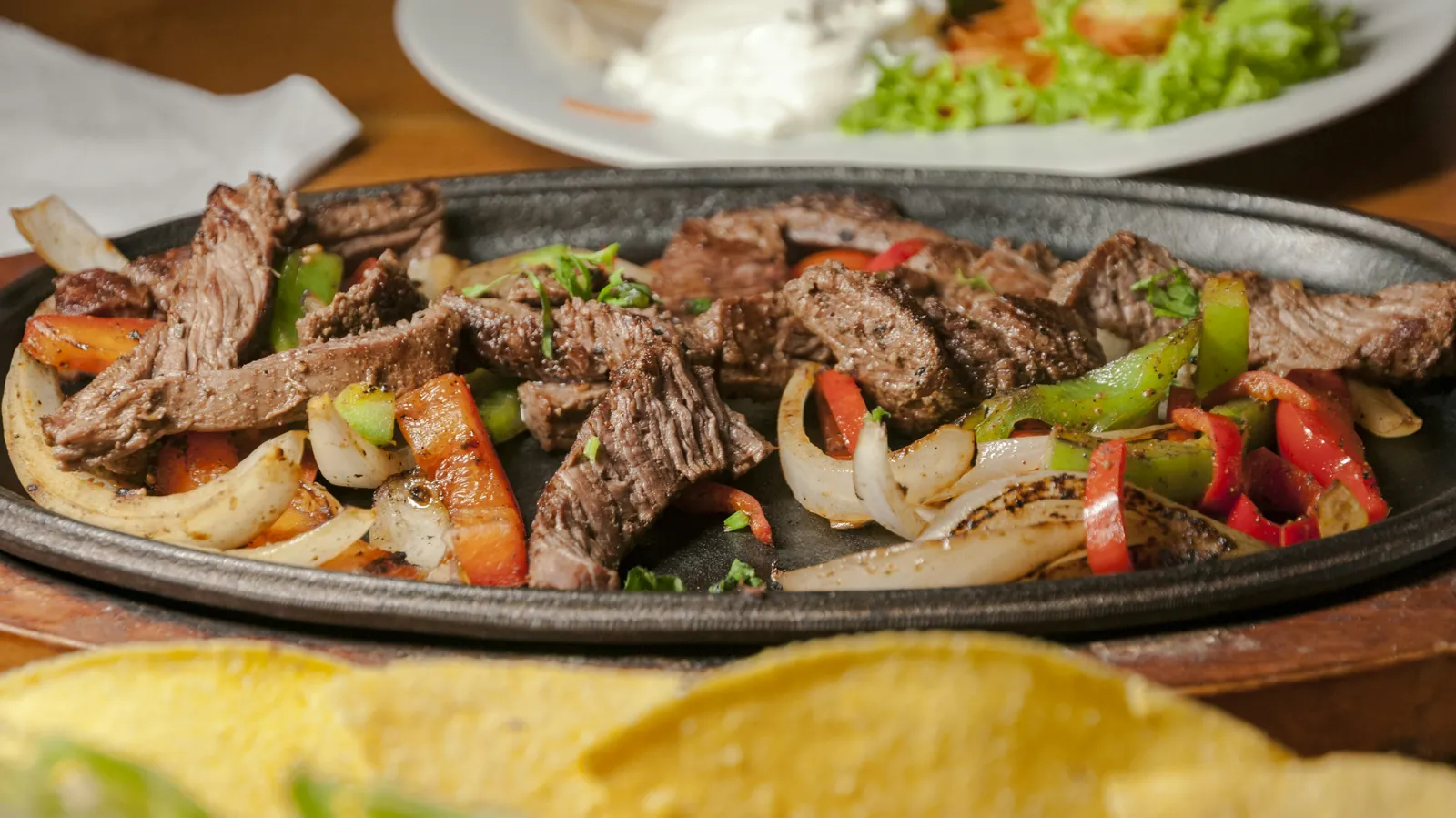 Beef fajitas with grilled peppers and onions on a cast iron platter