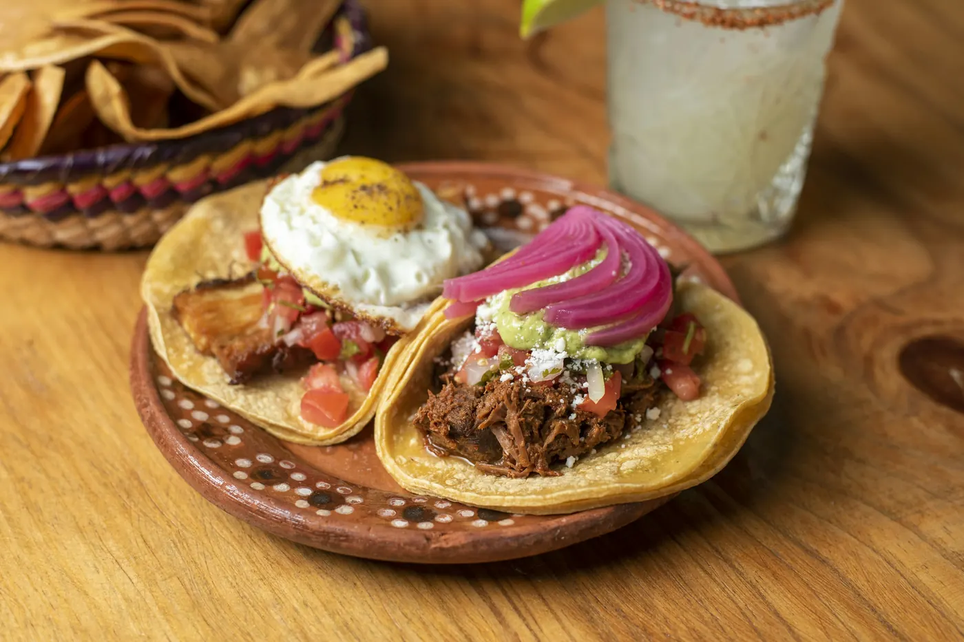 Corn tortillas filled with shredded meat, pickled onion and a fried egg