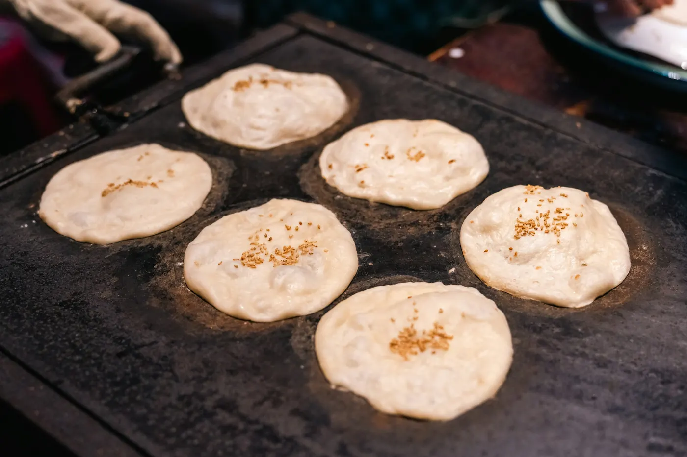 Thick rounds of masa cooking on a flat griddle