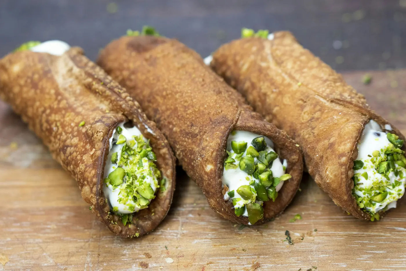 Three crisp rolled tortillas topped with cream, lettuce and cheese