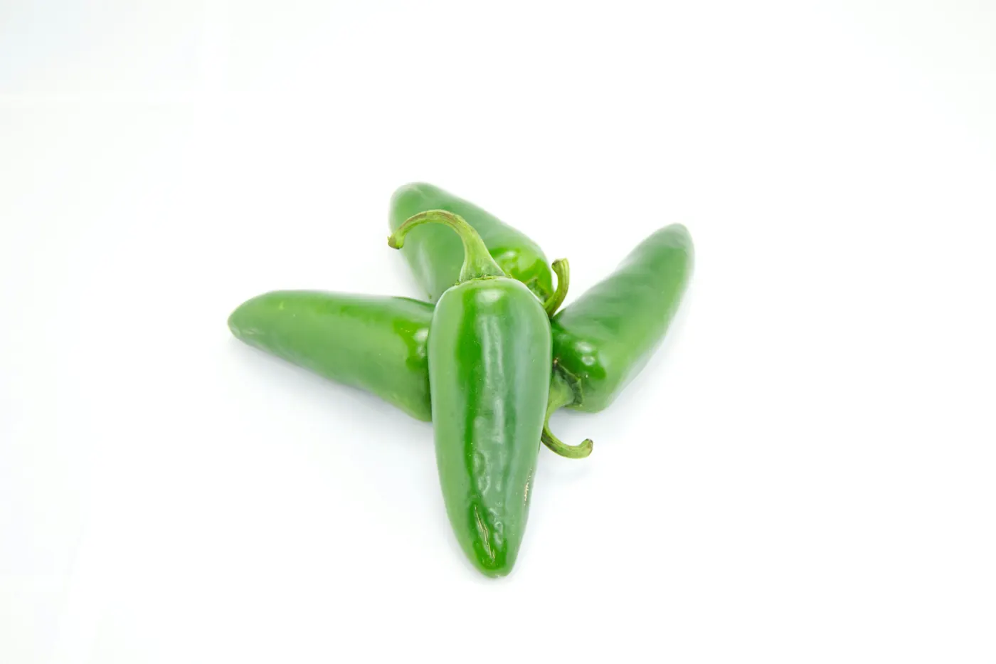 Three fresh green jalapeno peppers on a white background