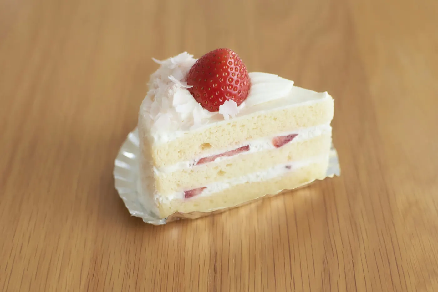 A slice of sponge cake layered with whipped cream and topped with a strawberry
