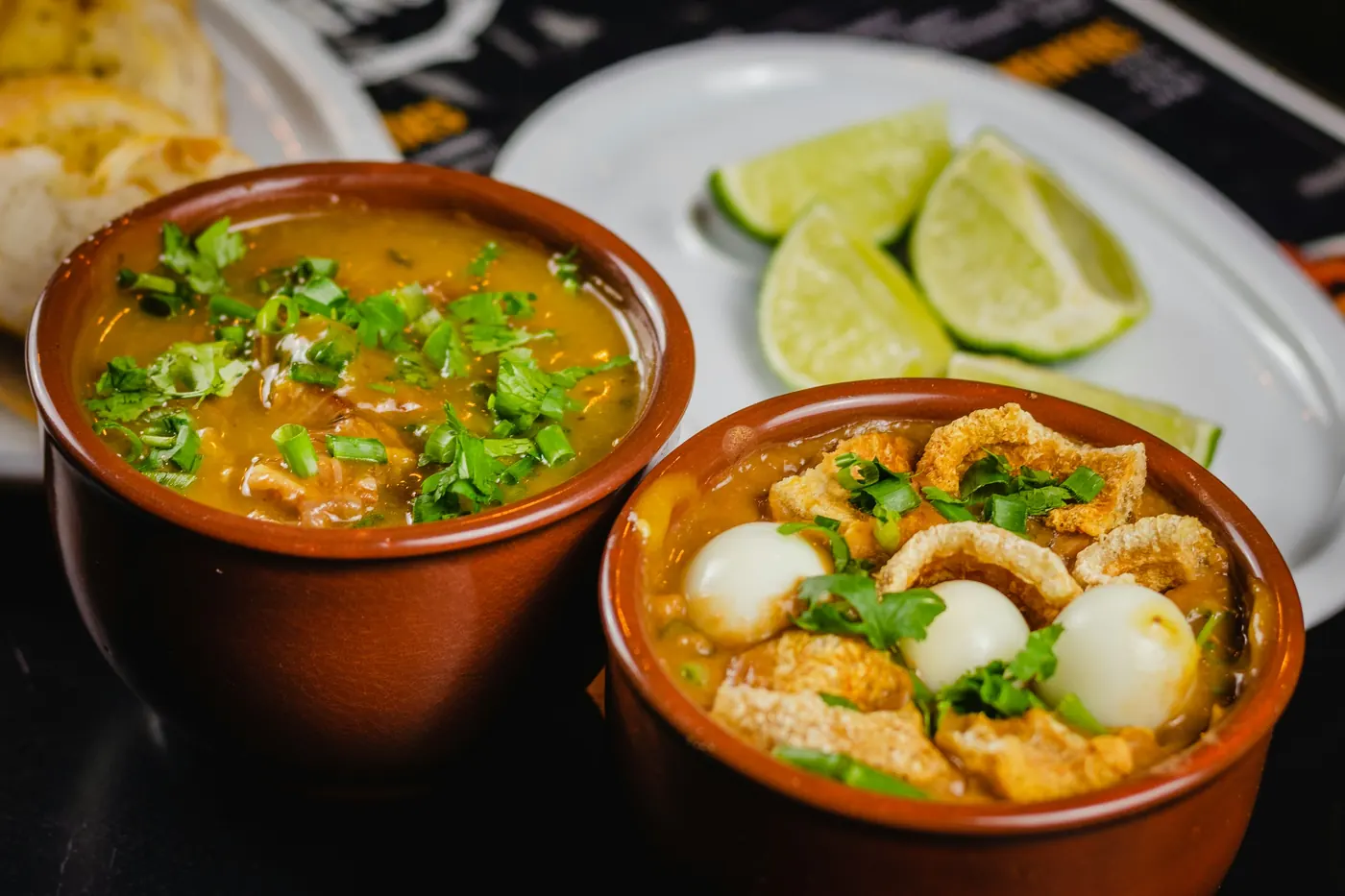 Two clay bowls of Mexican soup served with lime wedges