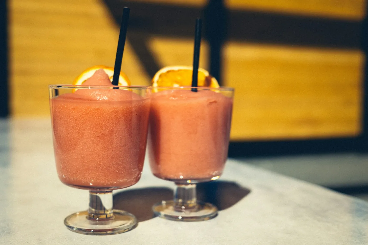 Two frozen strawberry margaritas served with straws