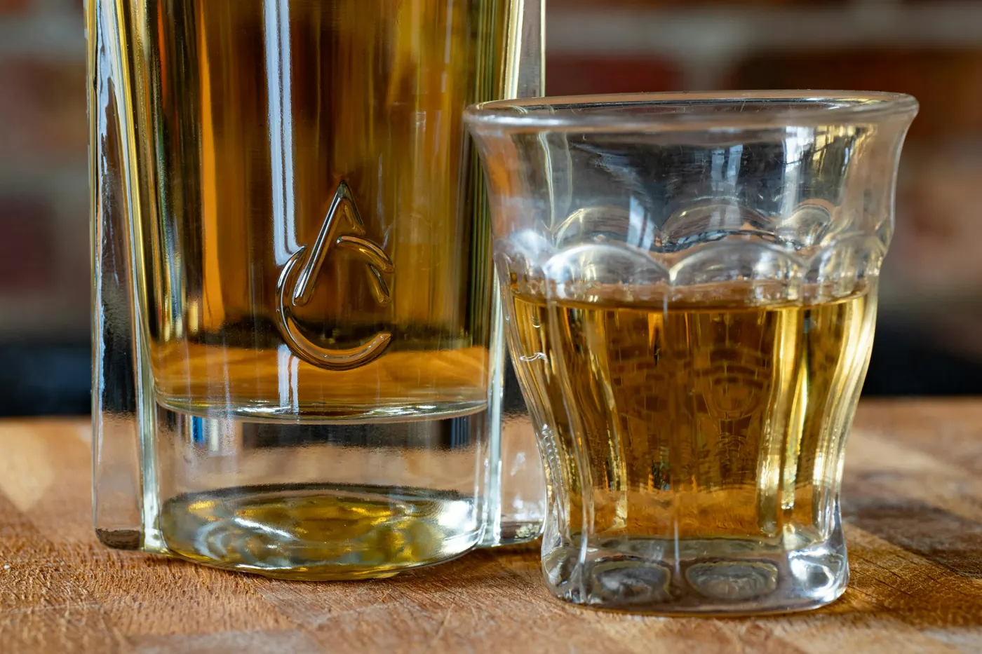 Two small glasses of amber-colored spirit on a wooden surface