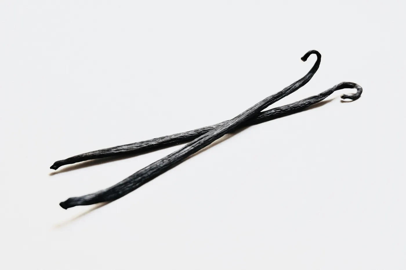 Two long dark vanilla pods on a plain white background