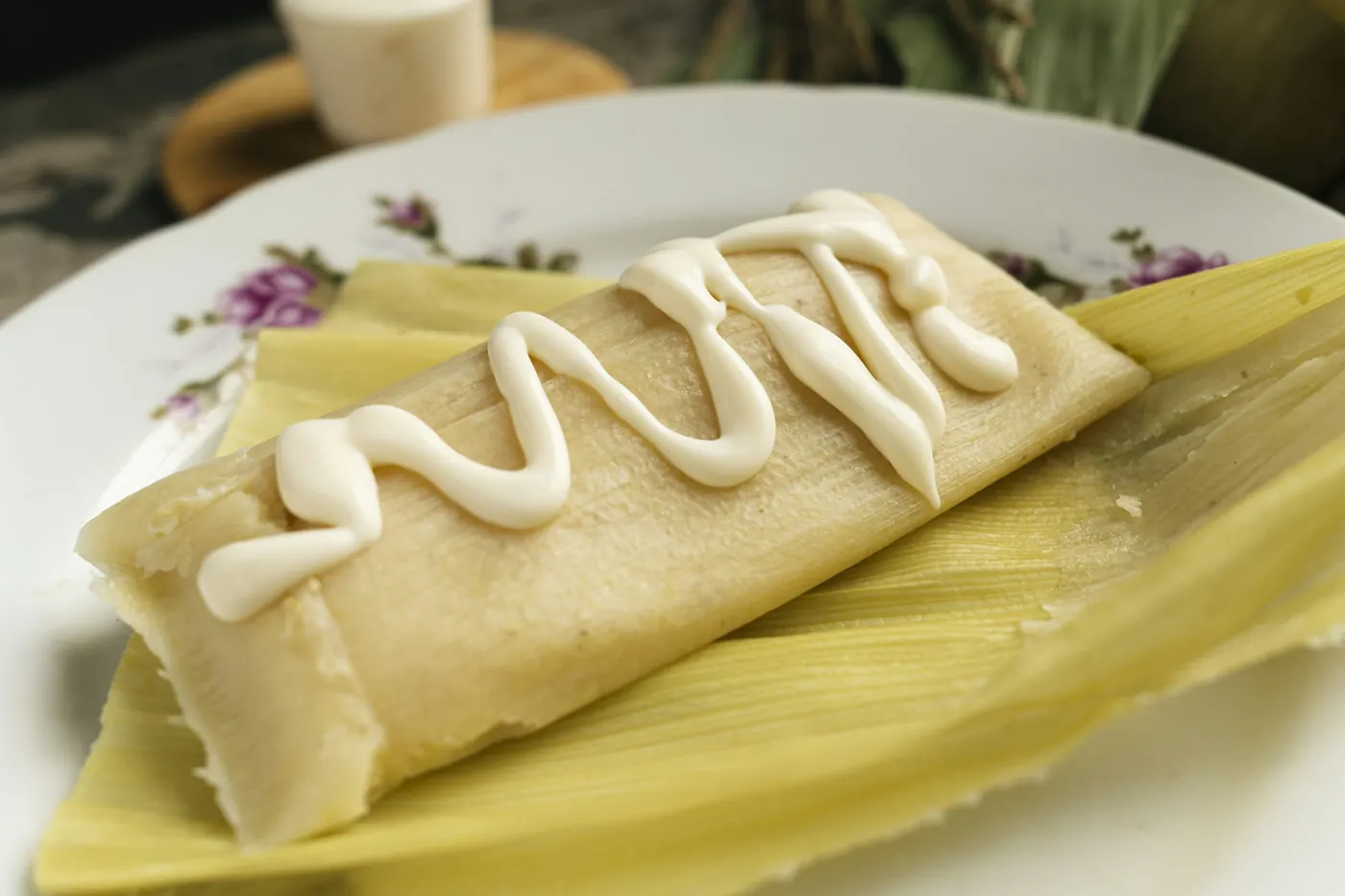 An unwrapped tamal on a plate, showing the pale masa inside