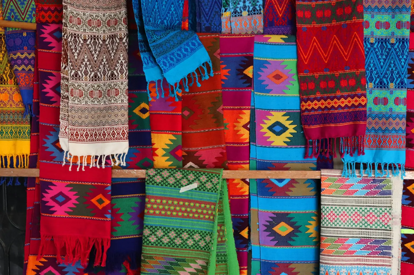 Stacks of woven textiles in bright colors at a market stall