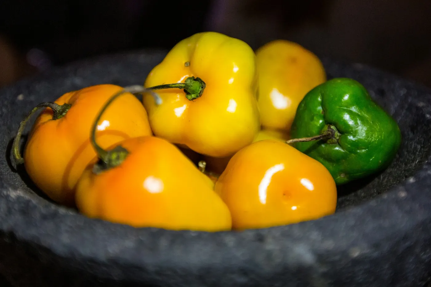 Yellow and orange habaneros sitting in a stone molcajete
